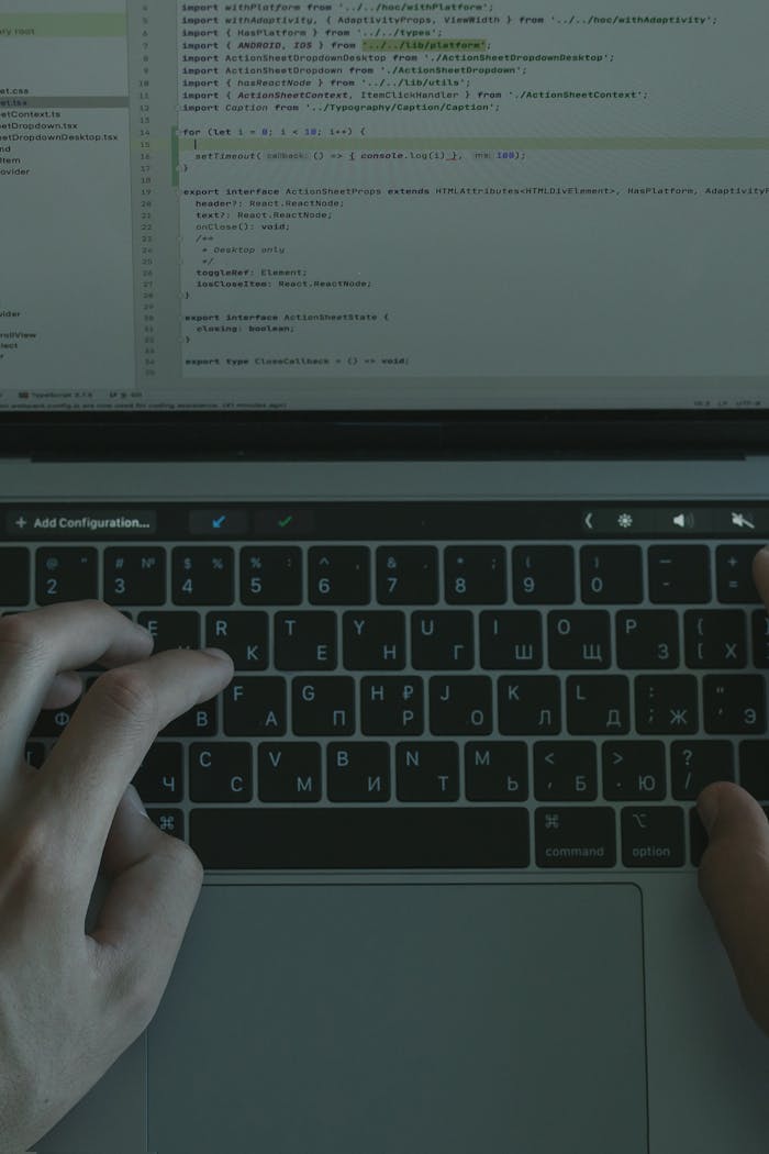 Hands typing on a laptop with a visible coding interface, showcasing technology use.